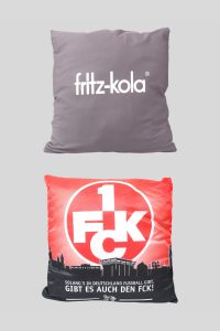 Zwei Kissen, eines mit fritz-kola Logo und das andere mit 1 FCK Aufdruck in roter Farbe.