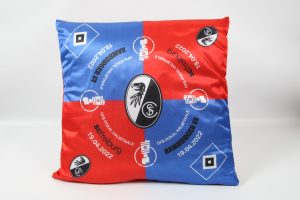Kissen in Rot und Blau mit SC Freiburg Logo und verschiedenen Texten in der Mitte.