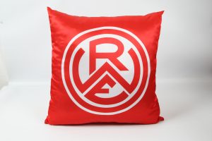 Rotes Kissen mit dem weißen RWE-Logo in der Mitte auf einem neutralen Hintergrund.