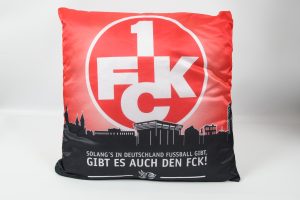 Kissen mit rotem und schwarzem Design, das das FCK-Logo und einen Spruch zeigt.