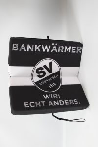 Schwarzes und weißes Sitzkissen mit dem Logo des SV Sandhausen und dem Schriftzug 'BANKWÄRMER'.