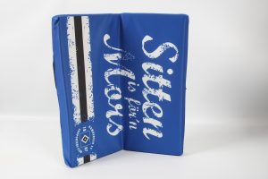 Blaues Klappkissen mit dem Schriftzug 'Sitzen ist fern' in weißer Schrift.