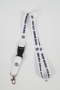 Weißes Schlüsselband mit dem Aufdruck 'DIE ELY. DEINE EINS.' und einem Karabinerhaken.