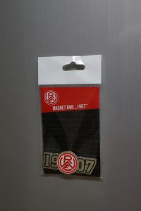 Magnet mit dem Schriftzug RWE und der Jahreszahl 1907 in einer transparenten Verpackung.