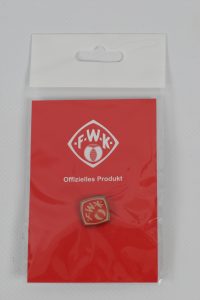 F-W-K Abzeichen in einer roten Verpackung mit dem Schriftzug 'Offizielles Produkt'.
