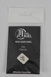 Ein klassischer Pin des THW Kiel, verpackt in einer transparenten Tüte mit schwarzem Hintergrund.