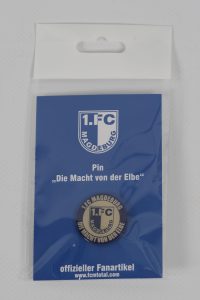 Pin des 1. FC Magdeburg mit dem Slogan 'Die Macht von der Elbe' auf blauer Verpackung.