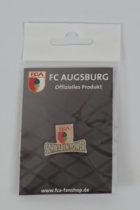 Anstecker mit dem Logo des FC Augsburg und dem Schriftzug 'Schwaben Power' in einer Verpackung.