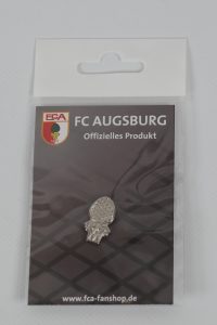 Anstecker des FC Augsburg in einer transparenten Verpackung mit Logo und Produktinformationen.