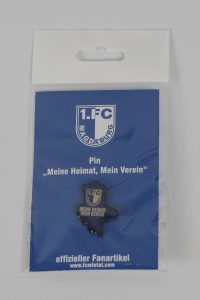 Pin des 1. FC Magdeburg mit dem Slogan 'Meine Heimat, Mein Verein' auf blauer Verpackung.