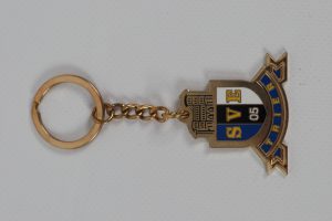 Metallischer Schlüsselanhänger mit dem Logo von SVE Trier und einer goldenen Kette.