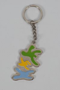 Metall Schlüsselanhänger mit drei bunten, stilisierten Formen in Grün, Gelb und Blau.