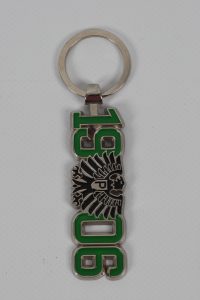 Metall Schlüsselanhänger mit grünem Text und einem Adler-Symbol, das die Jahreszahl 1906 zeigt.