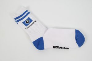Weiße Sportsocke mit blauen Streifen und schwarzem Schriftzug auf der Unterseite.