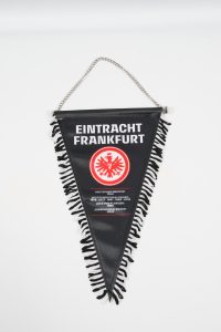 Schwarz-weißer Wimpel mit dem Logo von Eintracht Frankfurt und Fransen an der Unterkante.