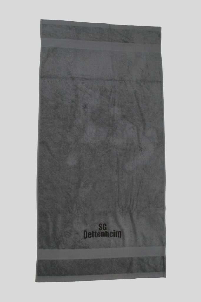 Ein Frottierhandtuch mit bedruckter Bordüre zeigt das Logo SG Dettenheim auf grauem Stoff und passt zum Produkt Handtücher bedruckt (50 x 100 cm).